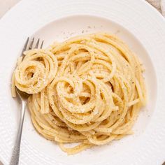 a white plate topped with pasta and a fork