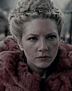 a woman wearing a red fur coat looking at the camera