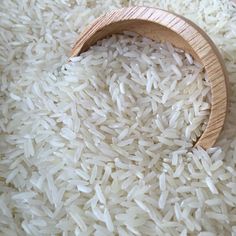 a wooden spoon filled with white rice on top of a table