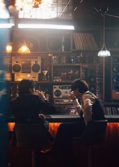 two people sitting at a bar in front of some sound equipment and lights hanging from the ceiling