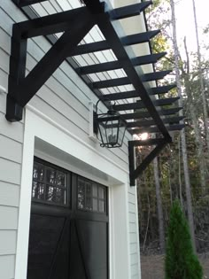 an open garage door with a lantern hanging from the ceiling and a black iron trellis over it