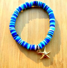 a blue and gold bracelet with a starfish charm on it's end sitting on a wooden surface