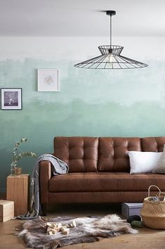 a living room with a brown leather couch and rugs on the wooden flooring