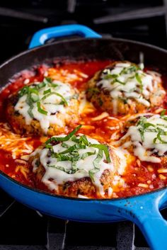 three meatballs covered in sauce and cheese on top of a blue skillet over an oven