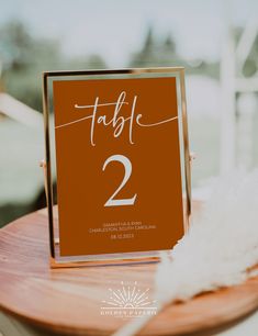 the table numbers are placed on top of a wooden plate with white feathers in front of it