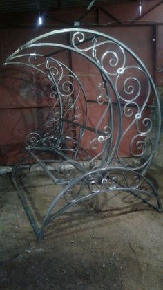 an iron bed frame sitting next to a red brick wall in a room with concrete flooring