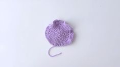 a purple crocheted hat sitting on top of a white table next to a pair of scissors