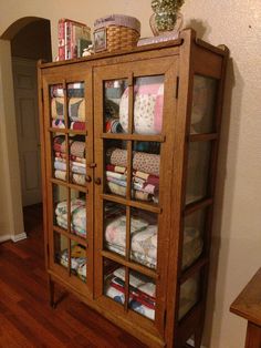 a wooden cabinet filled with lots of cloths on top of a hard wood floor