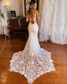 a woman standing in front of a piano wearing a wedding dress with an open back