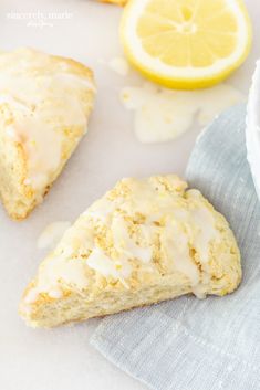 lemon scones with icing sitting on a napkin next to some sliced lemons