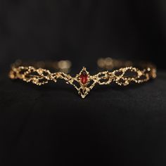 King's Crown features a beautiful gold colored metal braid formed into a circle highlighted by a red crystal at the center of the forehead. King's crown is tapered to fit just right and add the perfect touch.  Circumference: 6.5 Inches Height of Center: 1.25 Inches Ring Height: 0.25 Inches Crown is a disconnected circle and is adjustable to fit most hair styles and head shapes.  All items ship from Michigan, USA. WARNING: CHOKING HAZARD This item is not intended for use by children under the age of 5 years old.  There are small pieces that could fall off and create a choking hazard.  All use of this product by any minor, child or dependent should be supervised by an adult 18 years of age or older. Red Circlet Crown, Golden Circlet Crown, Gold Circlet Crown, Gold And Red Jewelry, Targaryen Jewelry, Blood Crown, Red And Gold Crown, Tiara Aesthetic, Forehead Crown