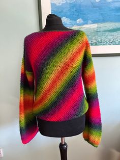 a woman's colorful sweater on a mannequin head stand in front of a painting