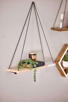 two hanging shelves with plants and books on them, one has a candle holder in the middle