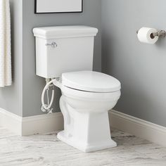 a white toilet sitting in a bathroom next to a roll of toilet paper on the wall