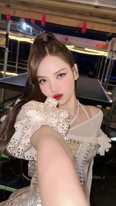 a woman with long brown hair wearing a white dress and posing for a photo in front of some chairs