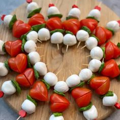 a wooden board topped with marshmallows and tomato slices on skewers