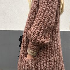 a close up of a woman's arm wearing a brown sweater and black pants