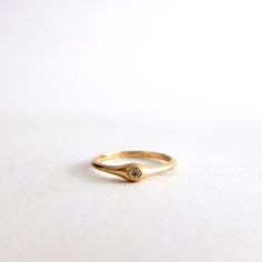 a gold ring with a single diamond on the top, sitting on a white surface