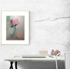 a pink rose in a vase on a white table