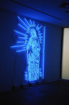 a blue neon sign with a statue of the virgin mary on it in a dark room