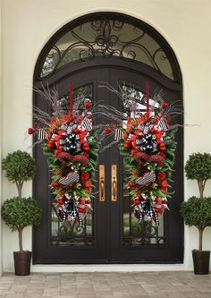 two christmas wreaths on the front door of a house with red and black decorations