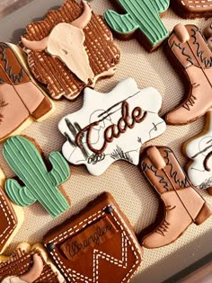 decorated cookies in the shape of cowboy boots and cacti are displayed on a tray