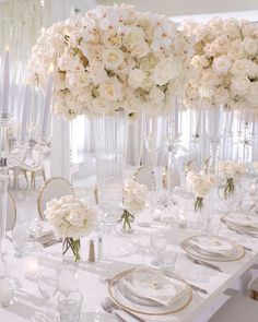 the table is set with white flowers and place settings for an elegant dinner party or reception