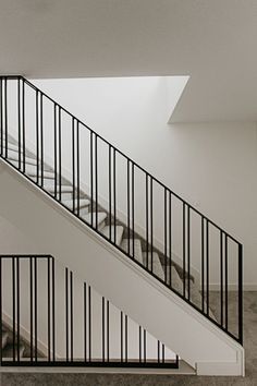 an empty staircase with black railings and white walls