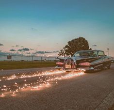 an old car driving down the road with sparklers on it