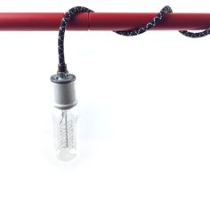 a light bulb is attached to a red pole with a black cord on it and an empty glass bottle in the middle