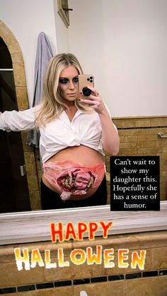 a woman taking a selfie with her cell phone in front of a mirror that says happy halloween