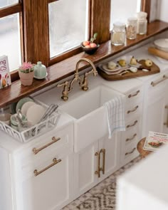 a white kitchen sink sitting under a window next to a counter top with dishes on it