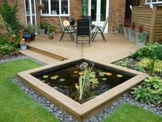 a wooden deck with a pond in the middle and chairs around it on top of grass