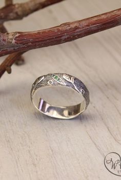 a silver ring sitting on top of a wooden table next to a twig branch