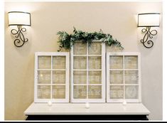 a couple of windows sitting on top of a white table next to a wall light