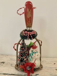 a snowman and christmas tree in a glass bottle with red ribbon around it's neck