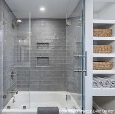 a walk in shower next to a white bath tub and shelves with towels on it