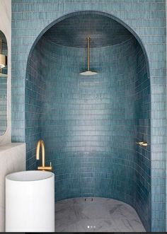 a bathroom with blue tile and gold fixtures on the walls, along with a round sink