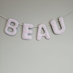 the word beau is hanging on a string with pinstripe fabric letters that spell out beau