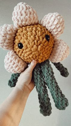 a hand holding a crocheted flower with black eyes