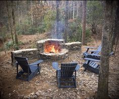 a fire pit surrounded by lawn chairs in the woods