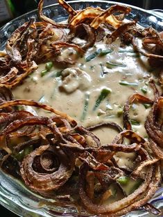 a glass plate topped with onion rings covered in gravy