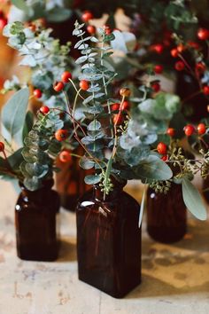 three brown vases filled with red berries and greenery