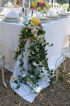 the table is set with white linens, flowers and greenery for an elegant dinner