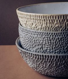 three bowls are stacked on top of each other, one is white and the other is gray