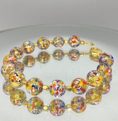 "Murano glass bracelet of 8mm beads with genuine 24k gold foil within each bead. Colorful and whimsical jewelry with an elegant touch! These glass beads are sourced from Artisans in Murano, Italy in Venice where they apply age old techniques to create these tiny works of art. Each bead is so charming with colors of red, orange, blue and yellow splattered within. Tiny gold beads accent the glass beads. The bracelet measures 7.25 inches with a Vermeil gold lobster claw clasp. ( Please measure your Venetian Glass Jewelry, Yellow Czech Glass Bracelets With Round Beads, Gold Bracelets With Colorful Beads For Party, Spiritual Gold Bracelets With Colorful Beads, Multicolor Gold Bangle Bracelet As A Gift, Gold Bangle Bracelet With Colorful Beads, Multicolor Bangle Gold Bracelet As A Gift, Multicolor Glass Bracelets For Party, Multicolor Polished Beads Crystal Bracelet For Gift