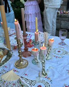 a table topped with lots of candles next to other items on top of a table