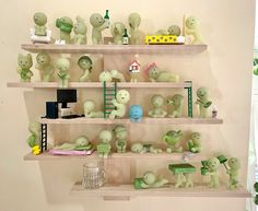 several shelves filled with different types of green plastic toys on top of wooden shelves next to a window