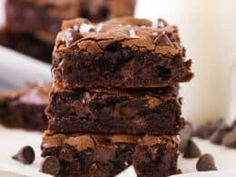 a stack of brownies sitting on top of a table next to a glass of milk