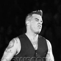 a black and white photo of a man with tattoos on his arm holding a microphone